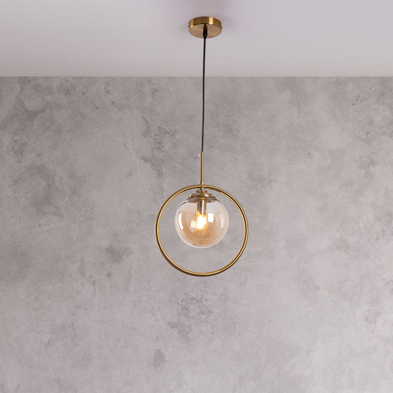 Globe Down Lighting Pendant Postmodern Clear/Amber/Smoke Grey Glass Single-Bulb Bedroom Suspension Light with Brass Ring Amber Clearhalo 'Ceiling Lights' 'Glass shade' 'Glass' 'Modern Pendants' 'Modern' 'Pendant Lights' 'Pendants' Lighting' 1937402