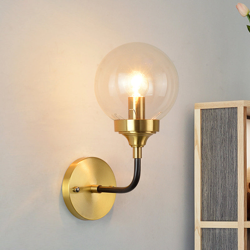 Simple Globe Wall Lighting Clear Glass 1 Bulb Sconce Light Fixture in Brass with Curved Arm Clearhalo 'Cast Iron' 'Glass' 'Industrial' 'Modern wall lights' 'Modern' 'Tiffany' 'Traditional wall lights' 'Wall Lamps & Sconces' 'Wall Lights' Lighting' 331357